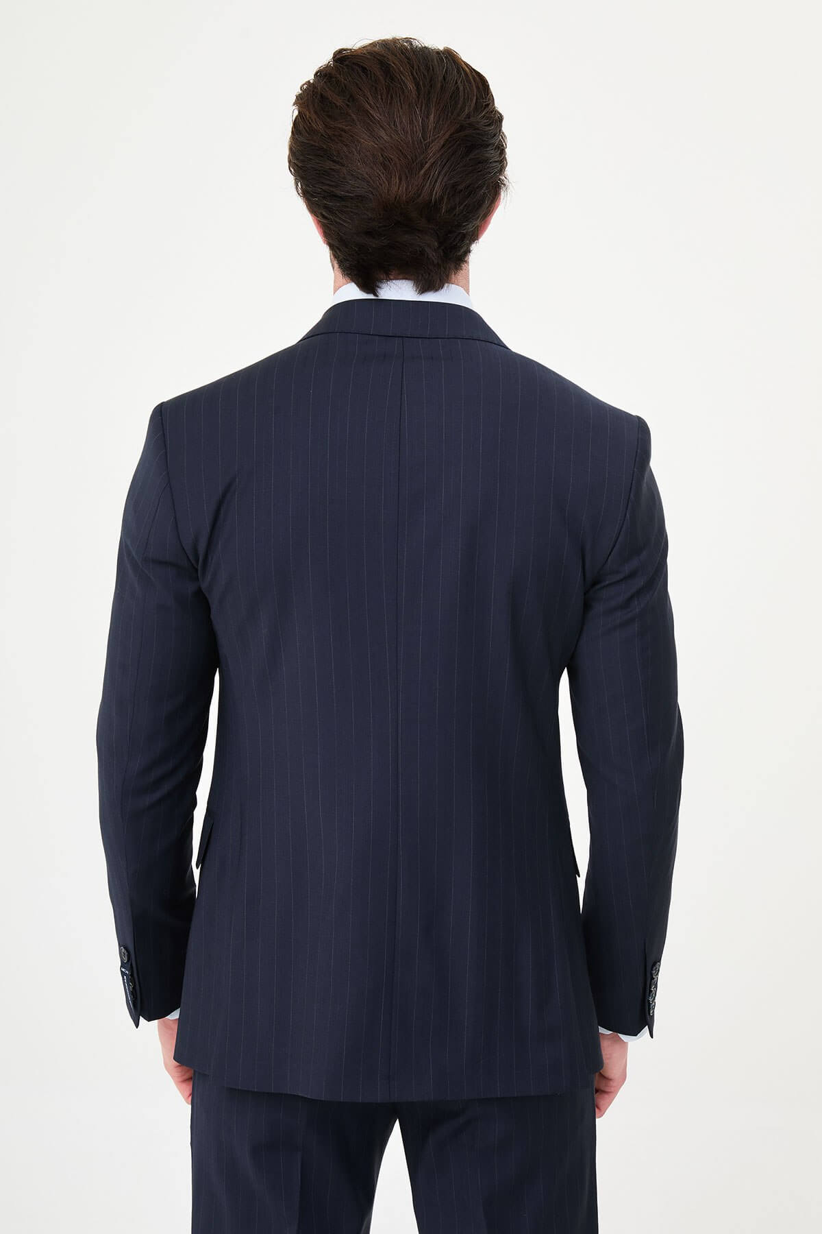 Man wearing a navy blue slim fit premium wool suit with wide collar, styled with matching trousers and a patterned tie