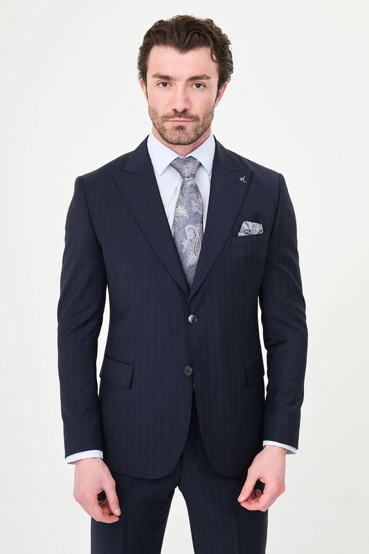 Man wearing a navy blue slim fit premium wool suit with wide collar, styled with matching trousers and a patterned tie