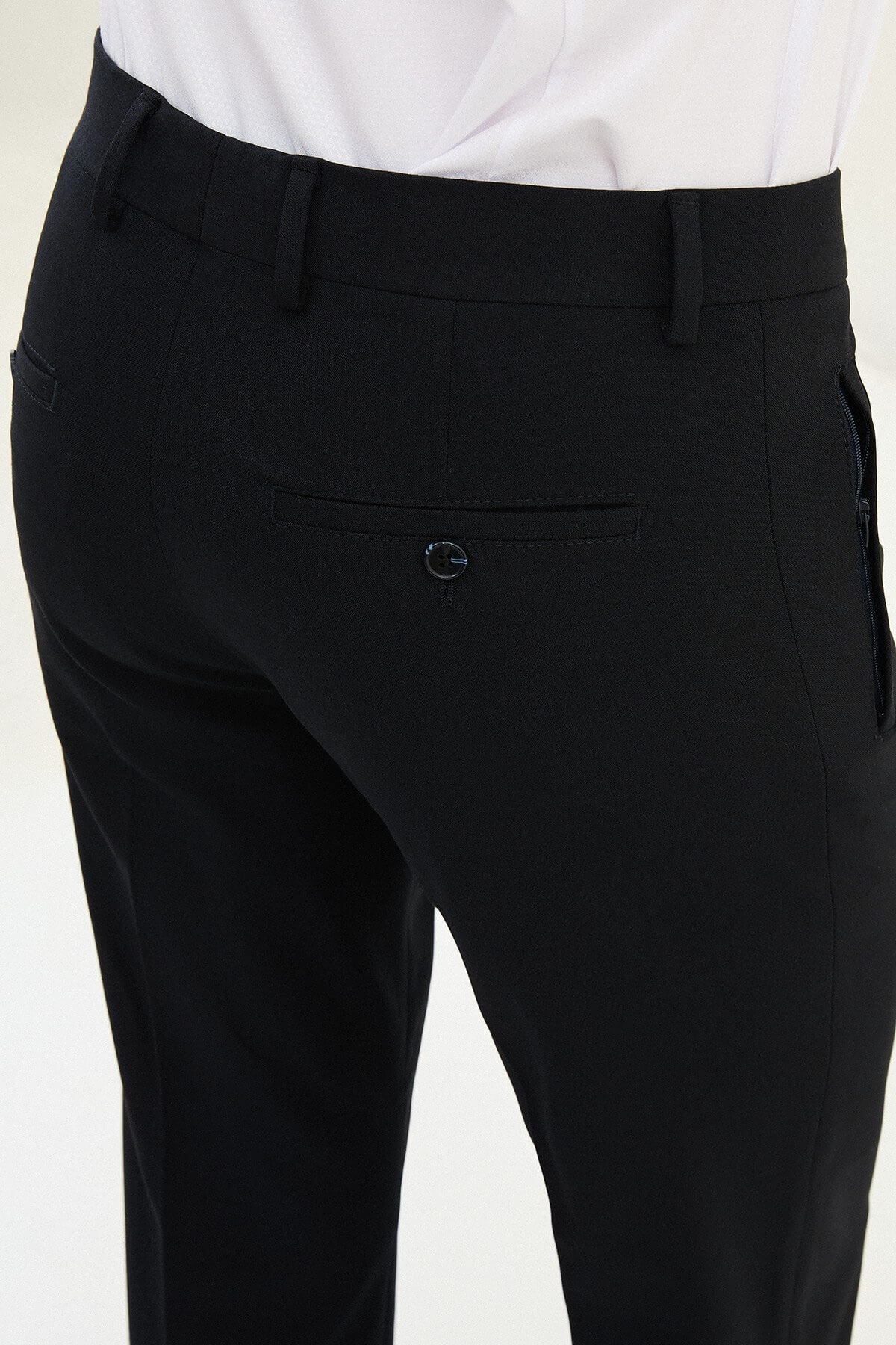 Man wearing navy blue slim-fit dress trousers styled with a white shirt and black leather shoes.
