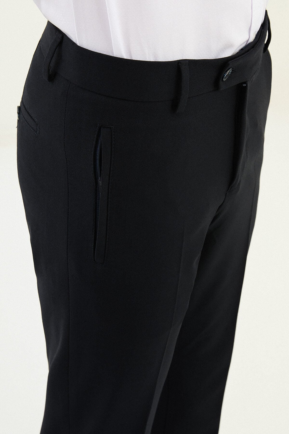 Man wearing navy blue slim-fit dress trousers styled with a white shirt and black leather shoes.