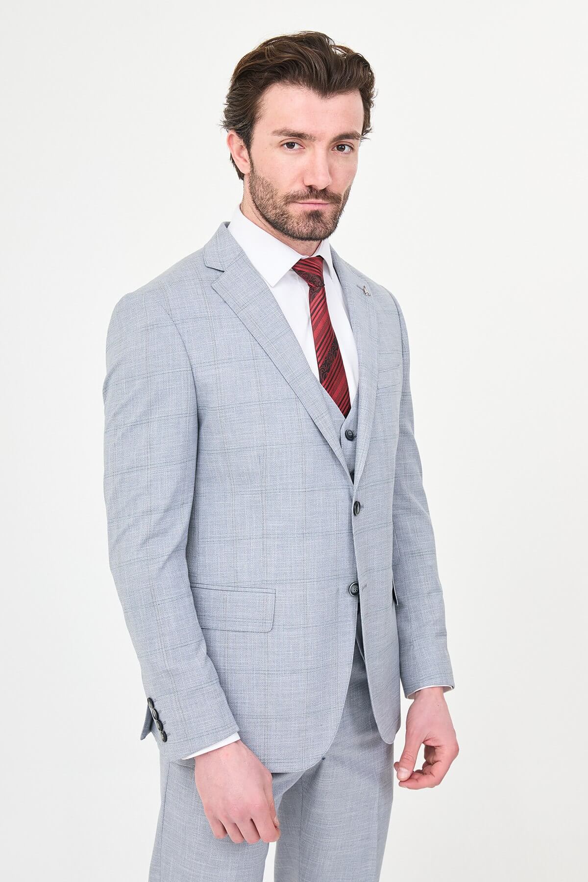 a navy blue slim-fit three-piece suit with a subtle windowpane check, matching waistcoat and trousers, white dress shirt, burgundy striped tie, and black leather Derby shoes.