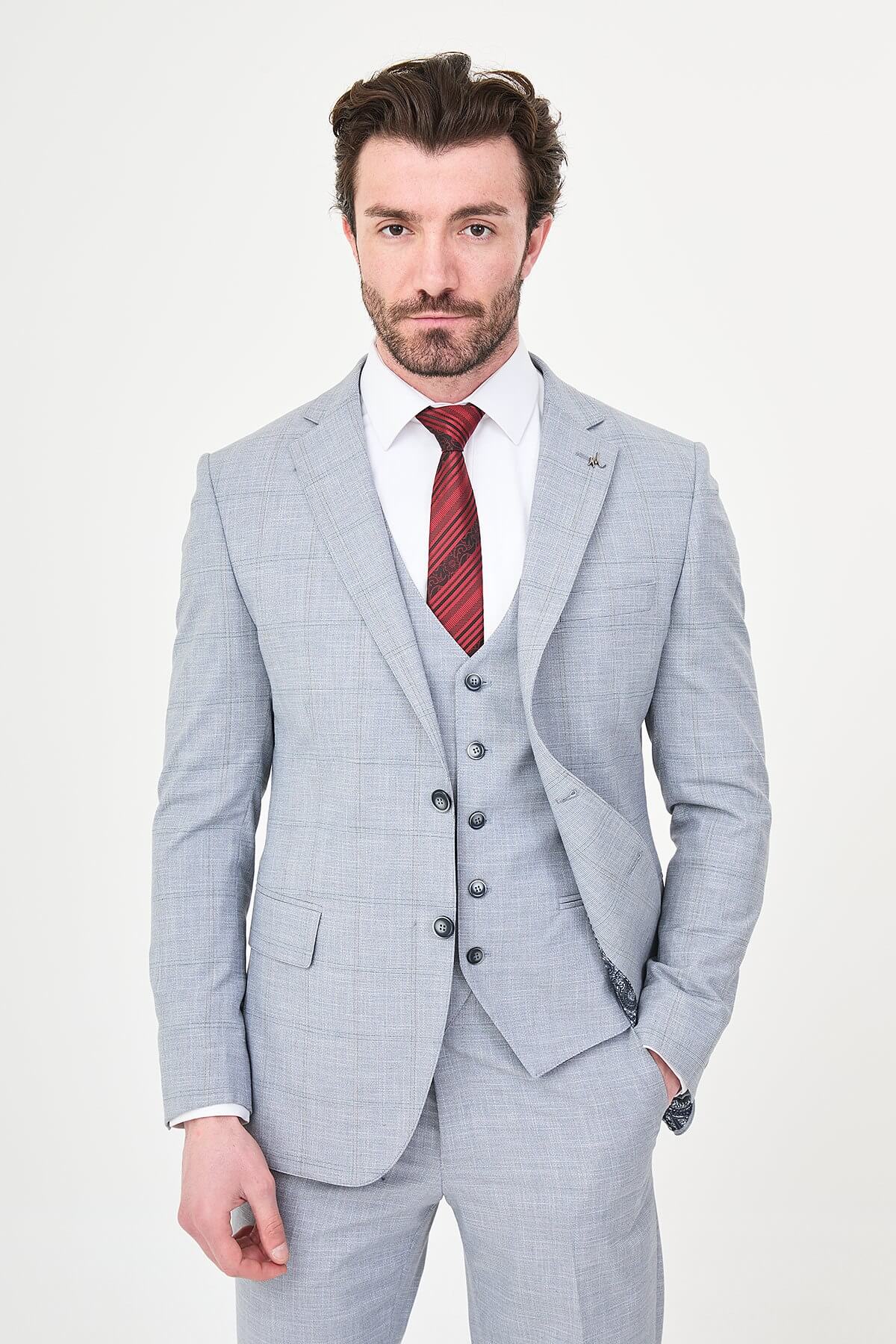 a navy blue slim-fit three-piece suit with a subtle windowpane check, matching waistcoat and trousers, white dress shirt, burgundy striped tie, and black leather Derby shoes.