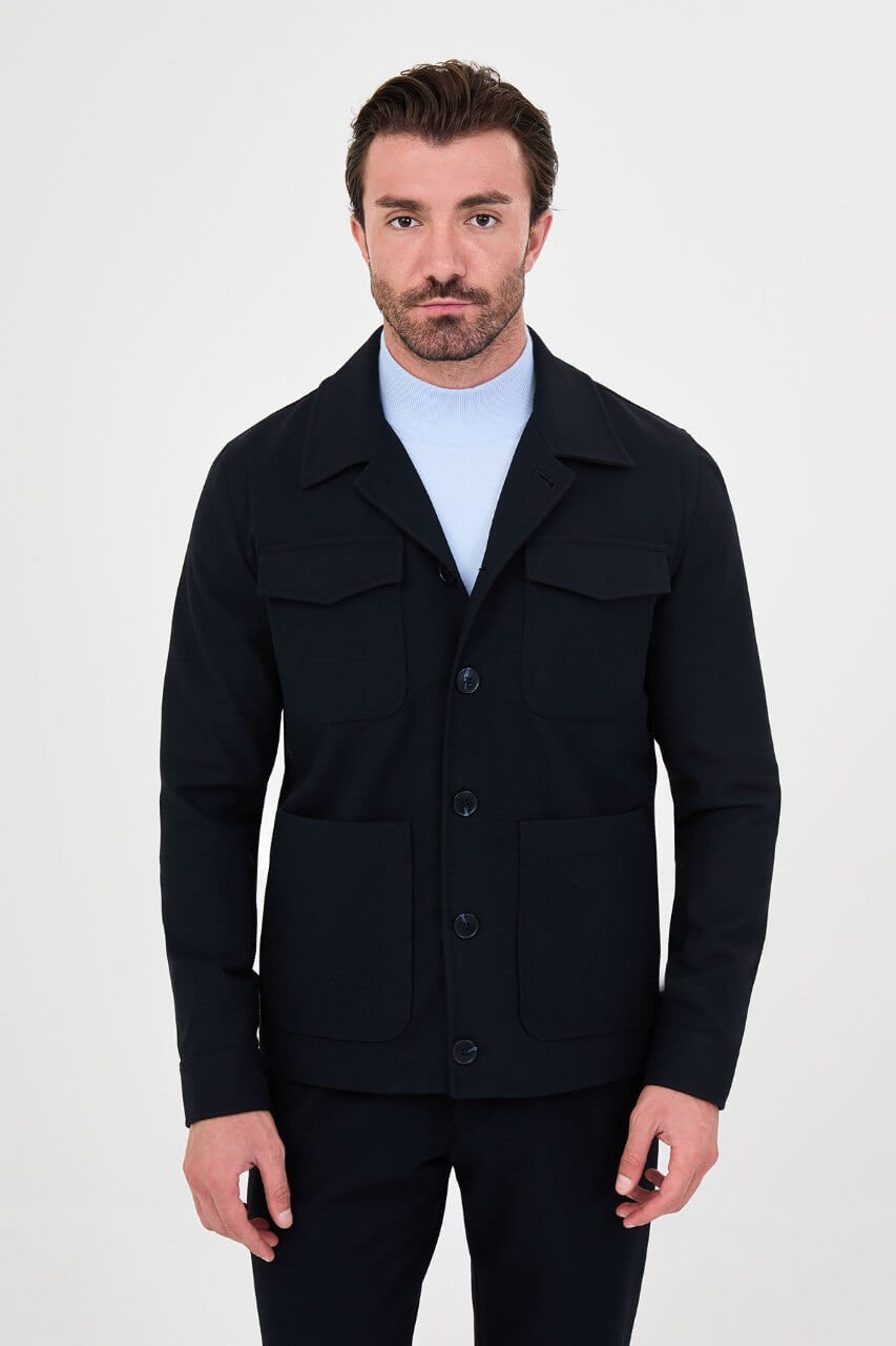 Men's navy blue fall jacket styled with a light blue sweater and dark trousers for a smart-casual look.