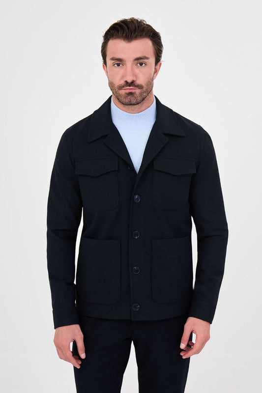 Men's navy blue fall jacket styled with a light blue sweater and dark trousers for a smart-casual look.