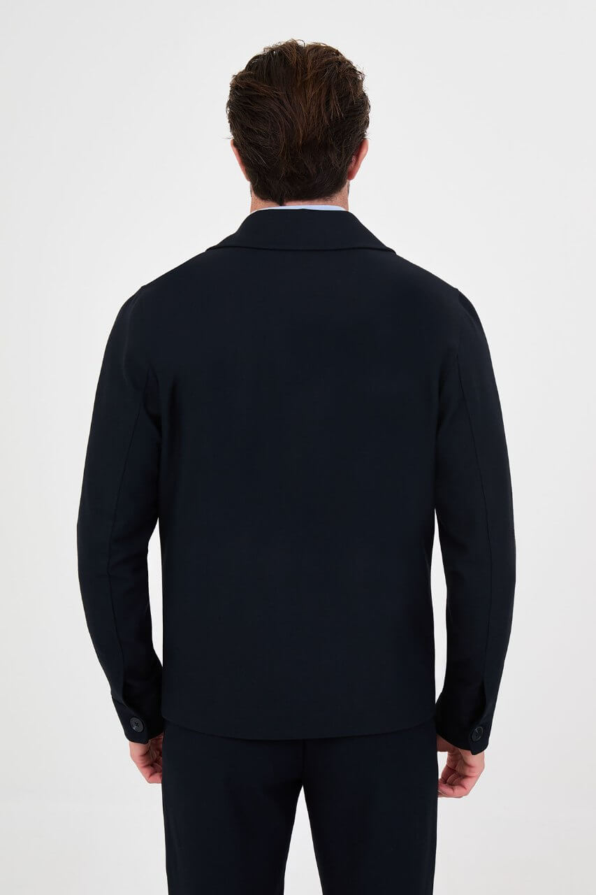 Men's navy blue fall jacket styled with a light blue sweater and dark trousers for a smart-casual look.