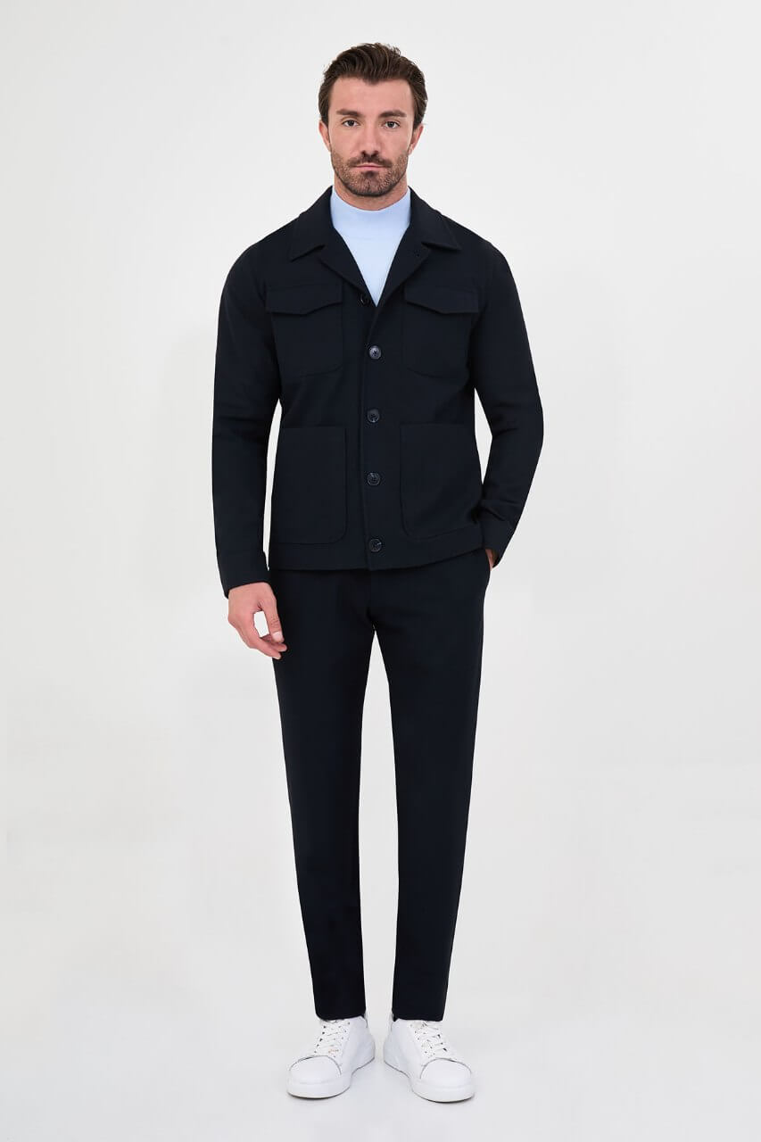 Men's navy blue fall jacket styled with a light blue sweater and dark trousers for a smart-casual look.