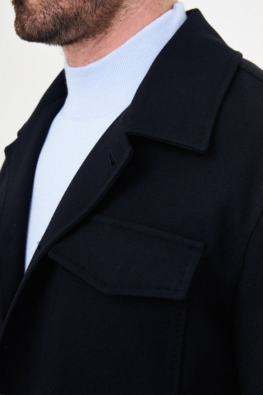 Men's navy blue fall jacket styled with a light blue sweater and dark trousers for a smart-casual look.