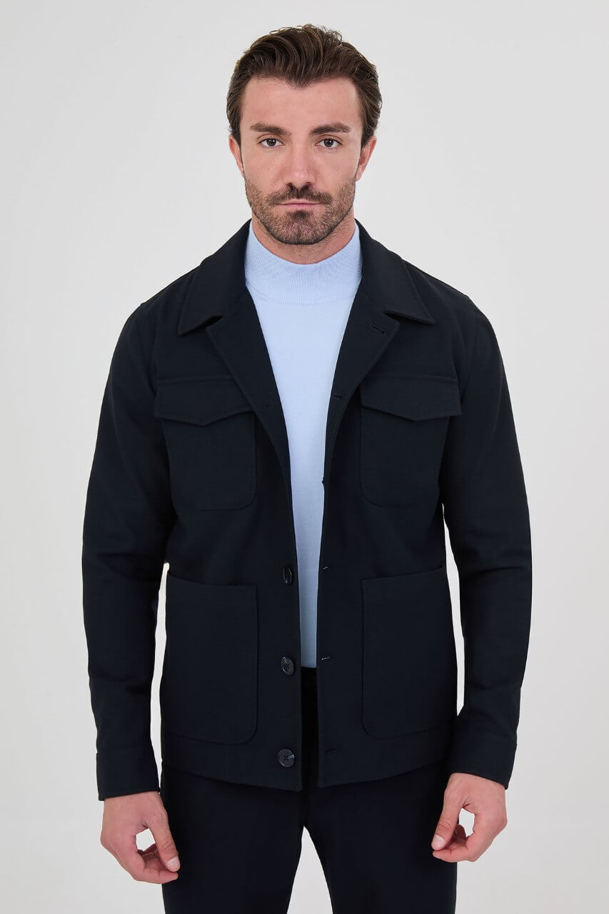 Men's navy blue fall jacket styled with a light blue sweater and dark trousers for a smart-casual look.
