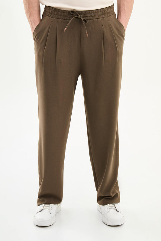 Men wearing olive brown luxe drawstring jersey pants with brown dress shoes, styled for a relaxed smart-casual summer look.