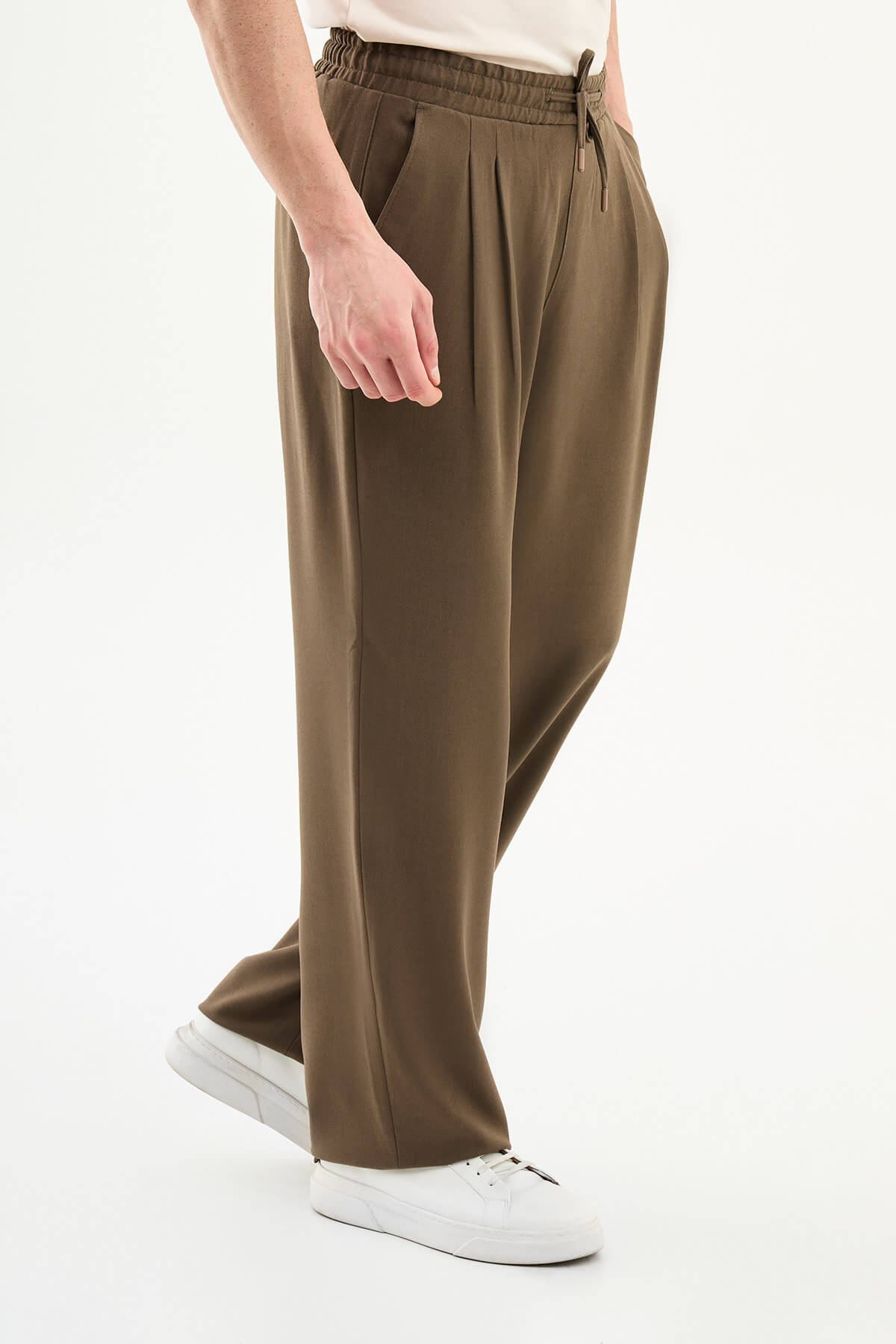 Men wearing olive brown luxe drawstring jersey pants with brown dress shoes, styled for a relaxed smart-casual summer look.