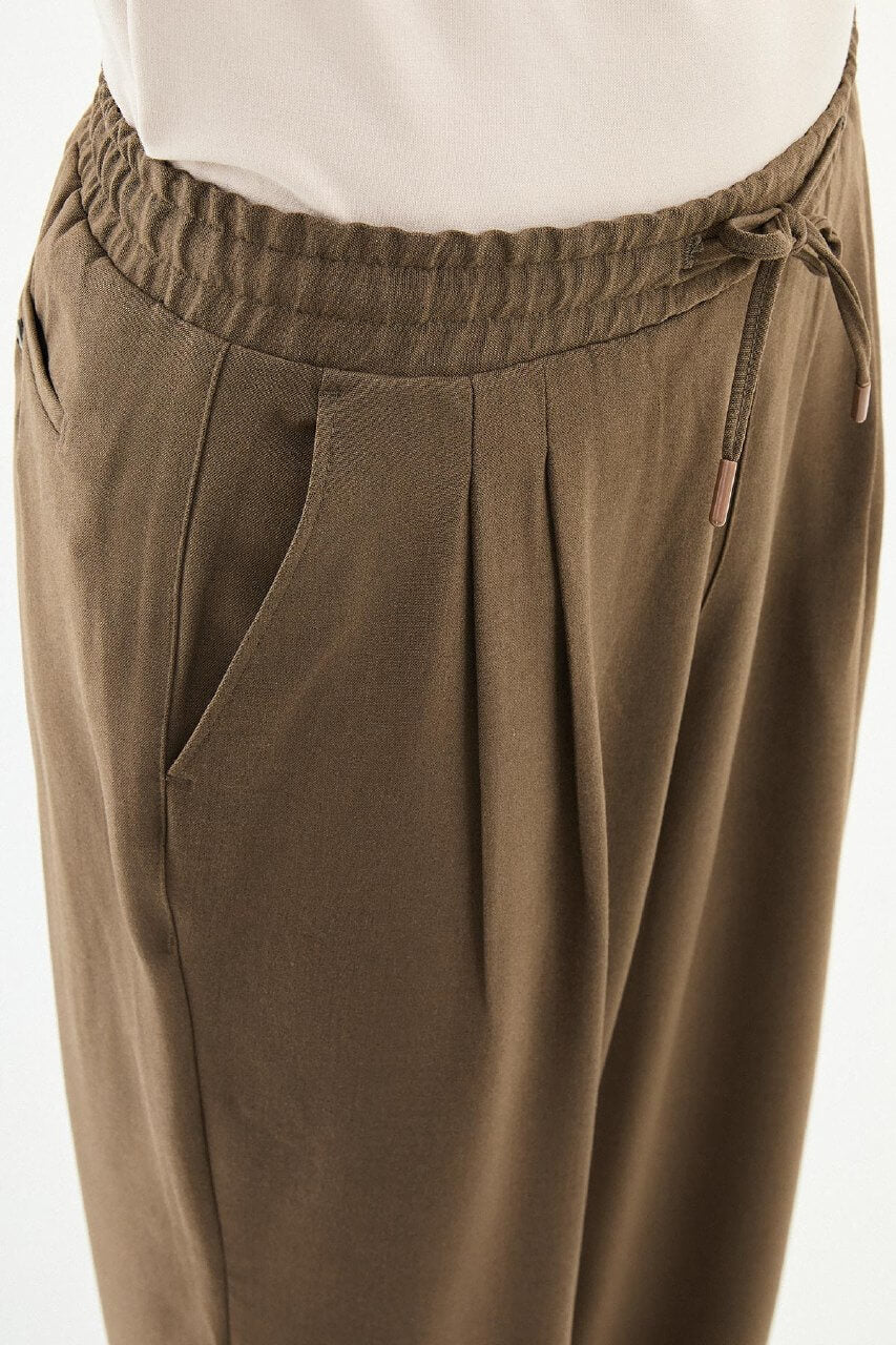 Men wearing olive brown luxe drawstring jersey pants with brown dress shoes, styled for a relaxed smart-casual summer look.
