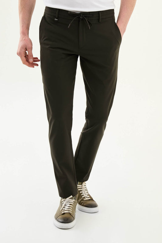 Man wearing olive green slim-fit summer trousers styled with a white polo shirt and casual sneakers.