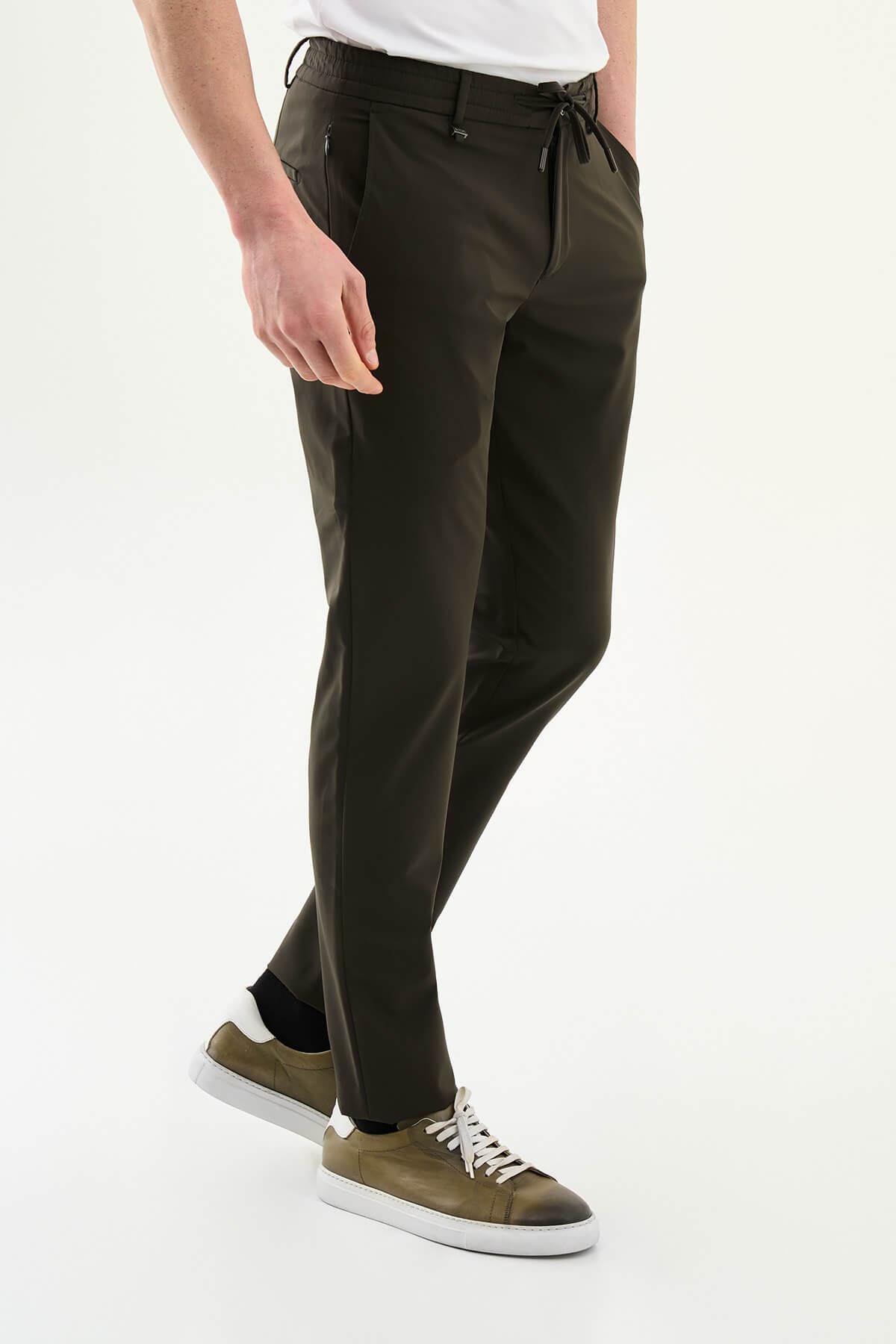 Man wearing olive green slim-fit summer trousers styled with a white polo shirt and casual sneakers.