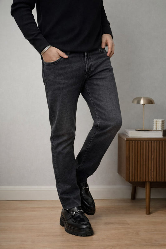 Black slim straight men’s jeans styled with black sweater and loafers