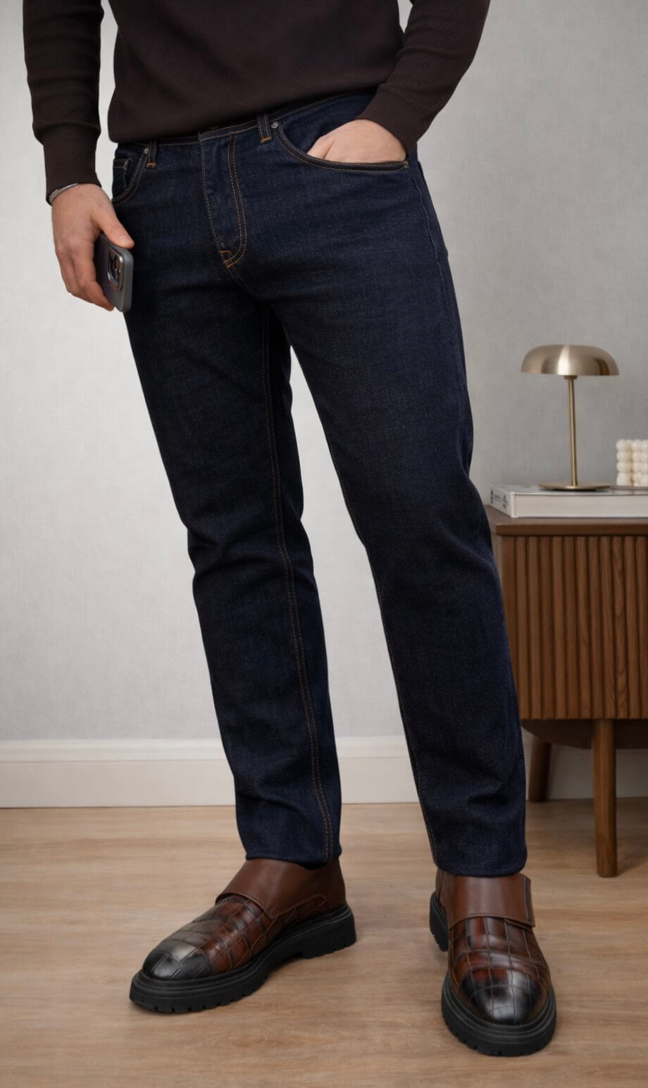 Dark blue slim straight men’s jeans styled with brown knit sweater and leather loafers