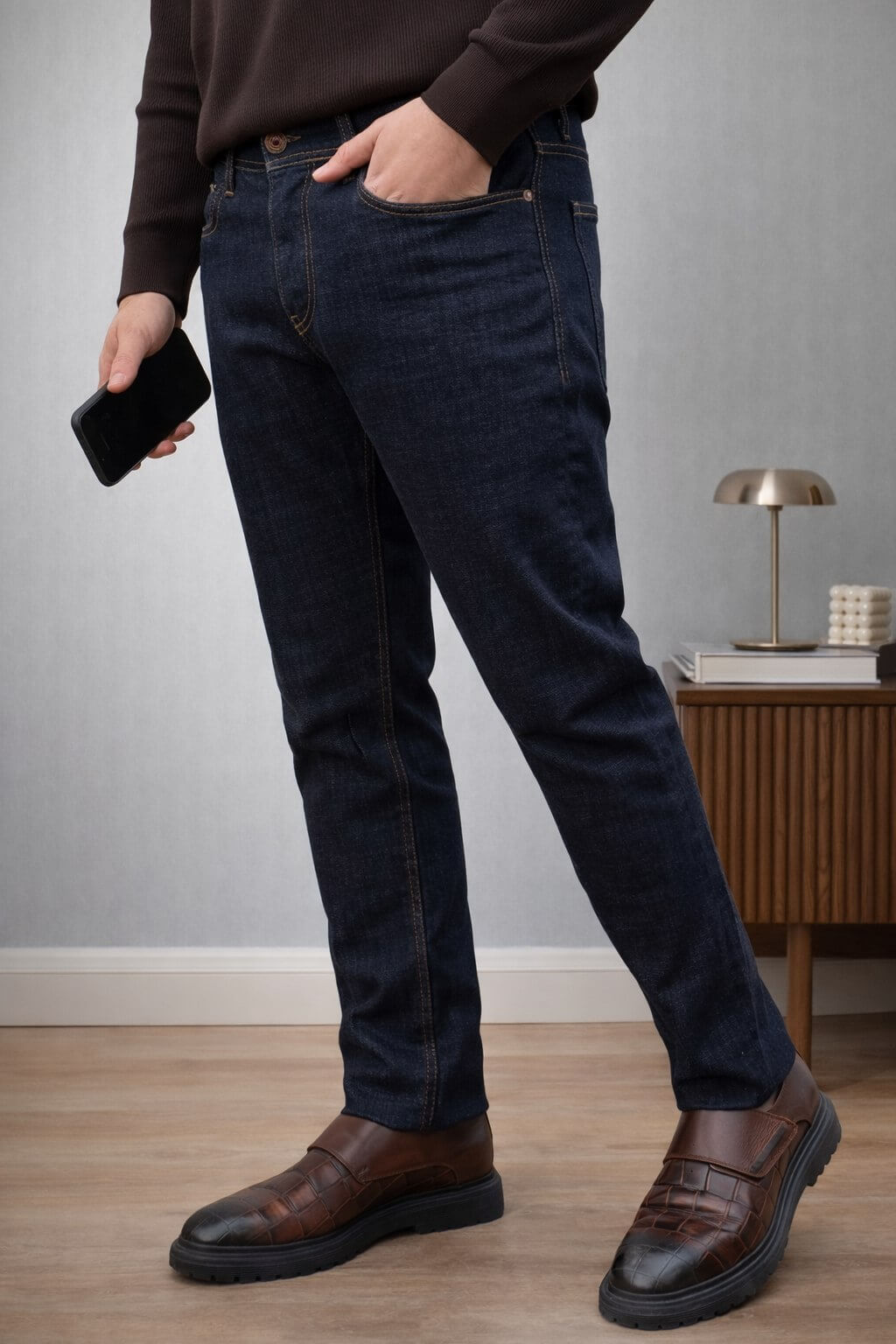 Dark blue slim straight men’s jeans styled with brown knit sweater and leather loafers