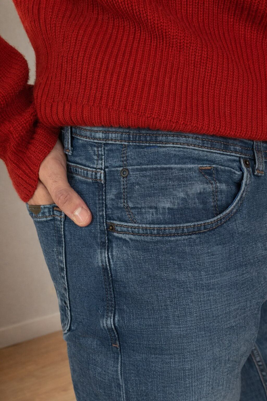 Blue slim straight men’s jeans styled with red knit sweater and white sneakers