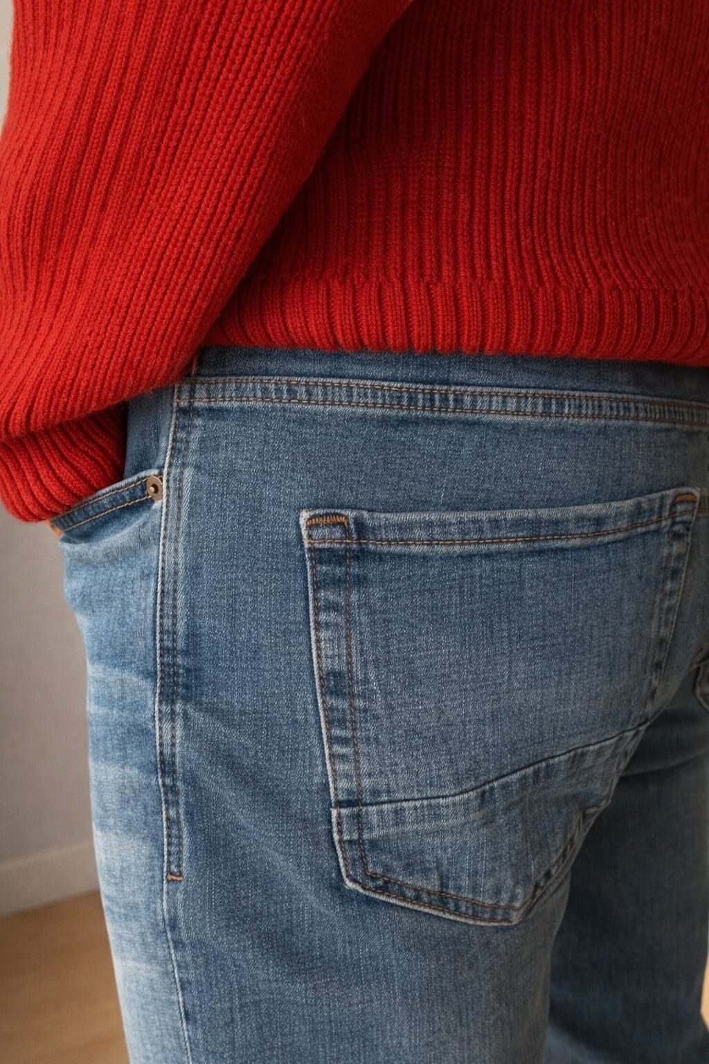 Blue slim straight men’s jeans styled with red knit sweater and white sneakers