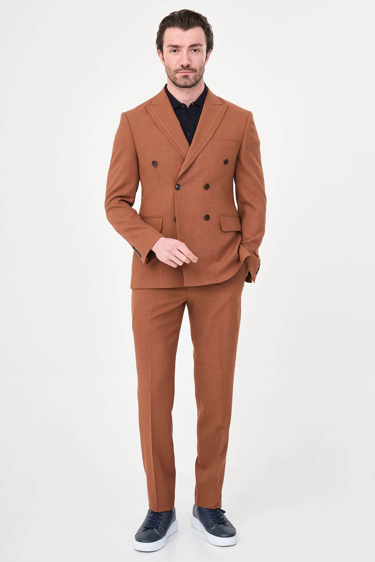 a Tile slim-fit double-breasted suit with peak lapels, contrast pick stitching, matching trousers, a black knit polo, and dark minimalist sneakers.