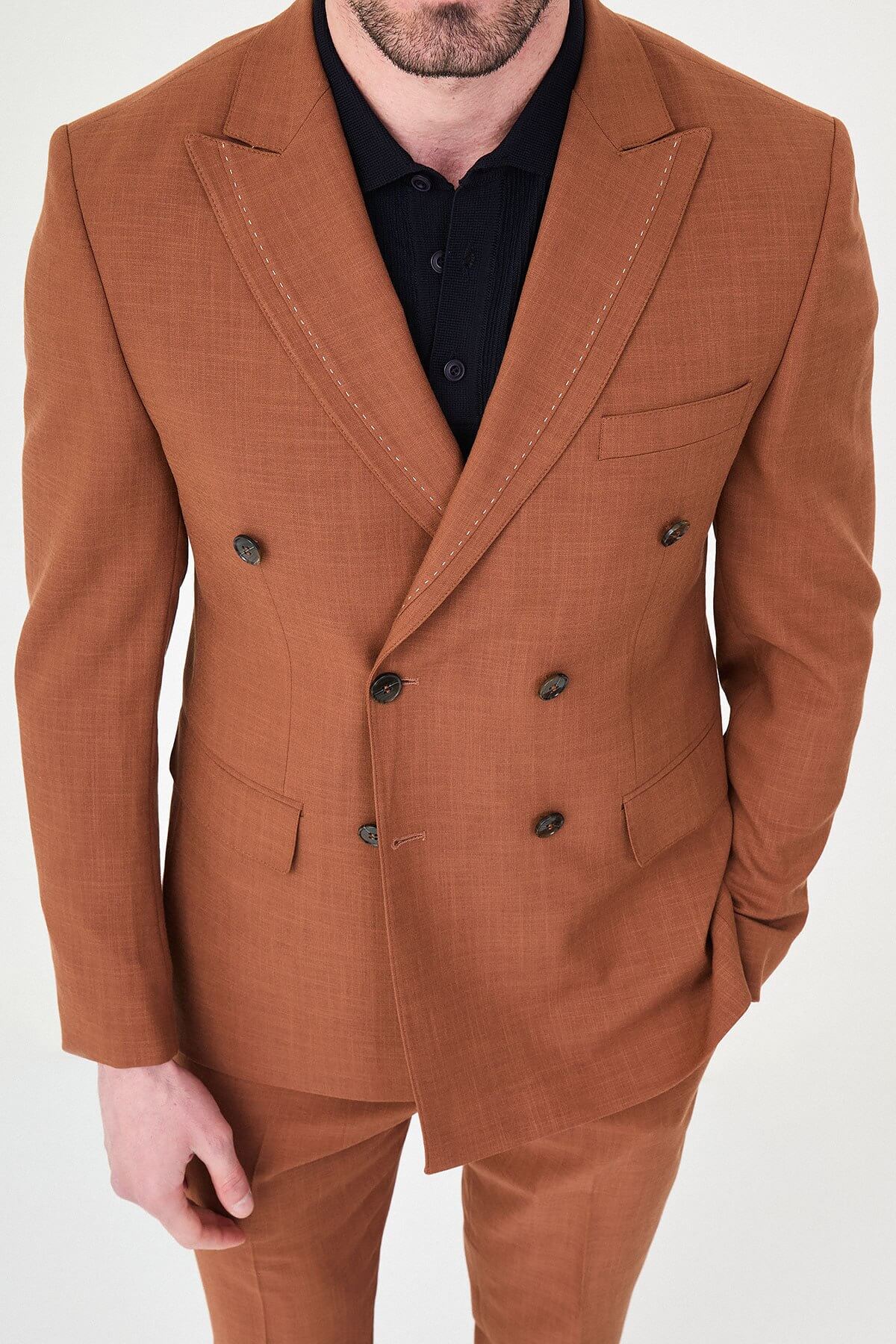 a Tile slim-fit double-breasted suit with peak lapels, contrast pick stitching, matching trousers, a black knit polo, and dark minimalist sneakers.