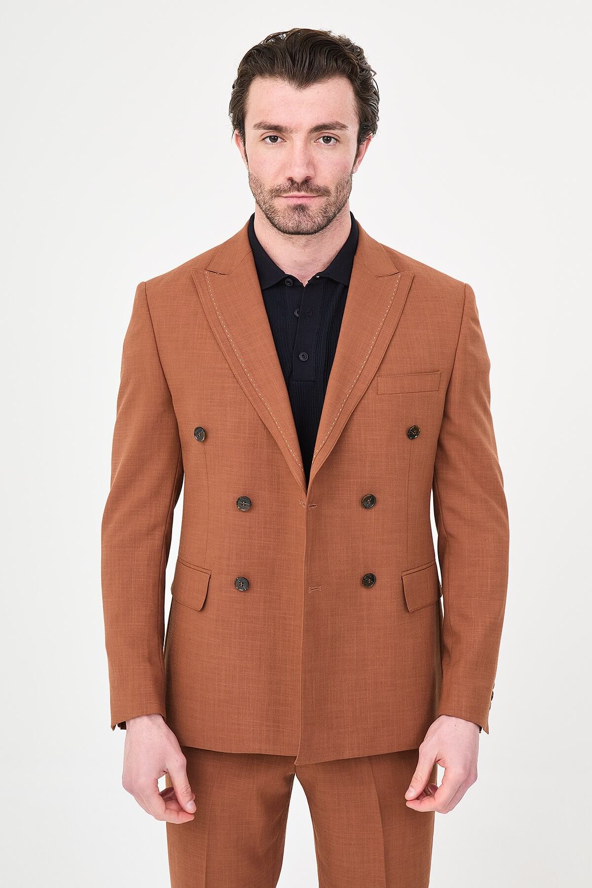 a Tile slim-fit double-breasted suit with peak lapels, contrast pick stitching, matching trousers, a black knit polo, and dark minimalist sneakers.