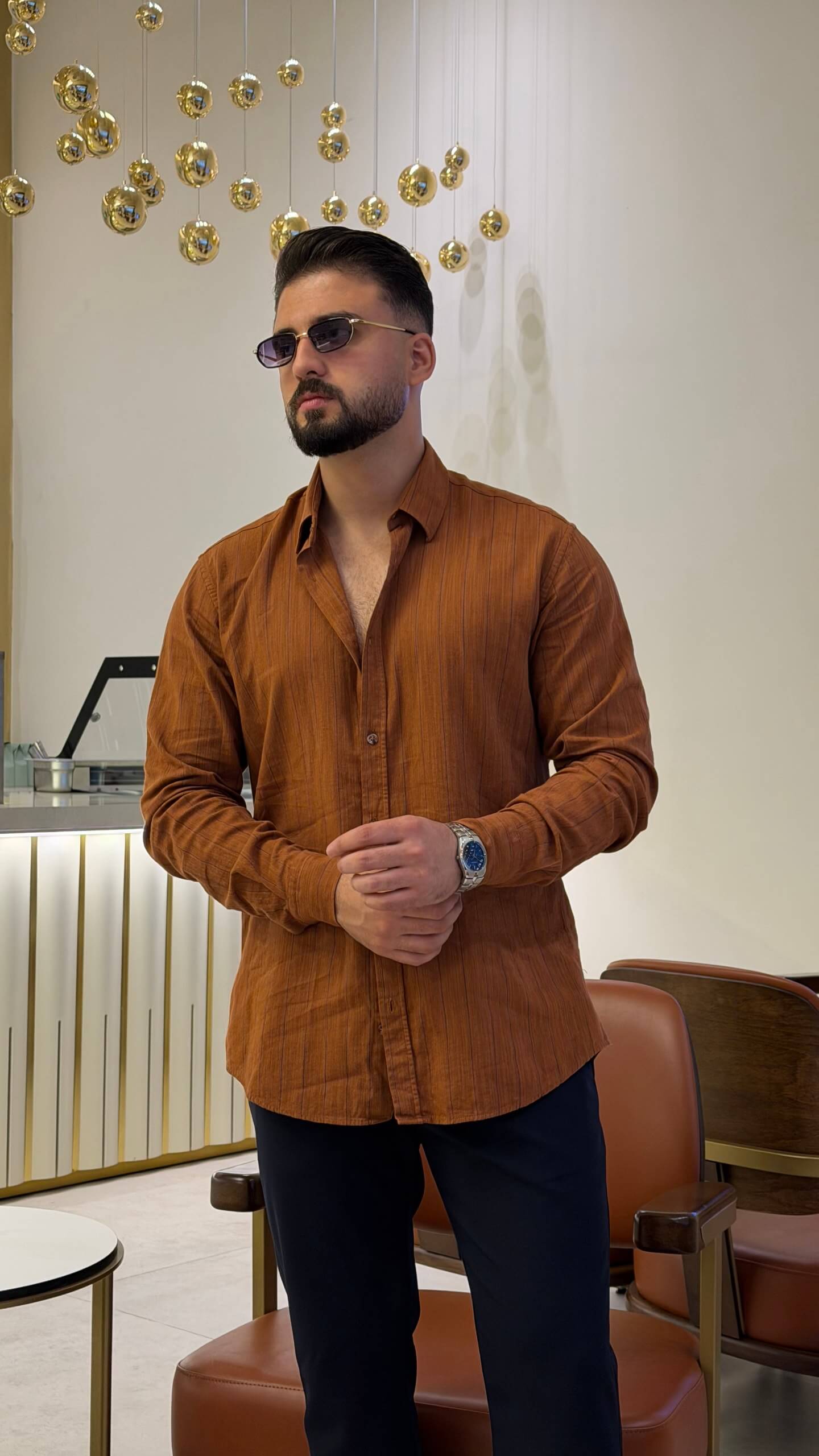 Men’s tile brown long sleeve cotton button-up shirt styled with black trousers and brown sneakers