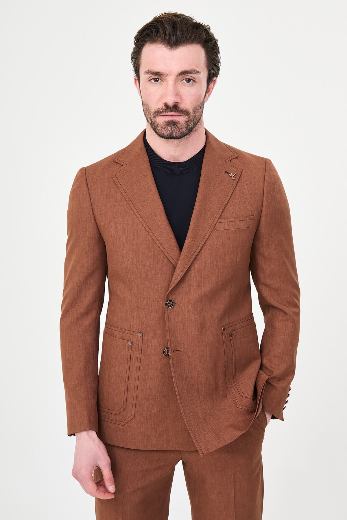 a tile slim-fit two-piece suit with notch lapels, utility-style stitched lower pockets, matching trousers, a black knit top, and brown leather shoes.