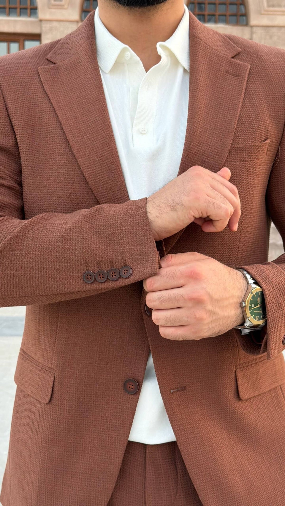 Men’s tile brown two piece suit with notch lapel jacket styled with white polo shirt and black loafers