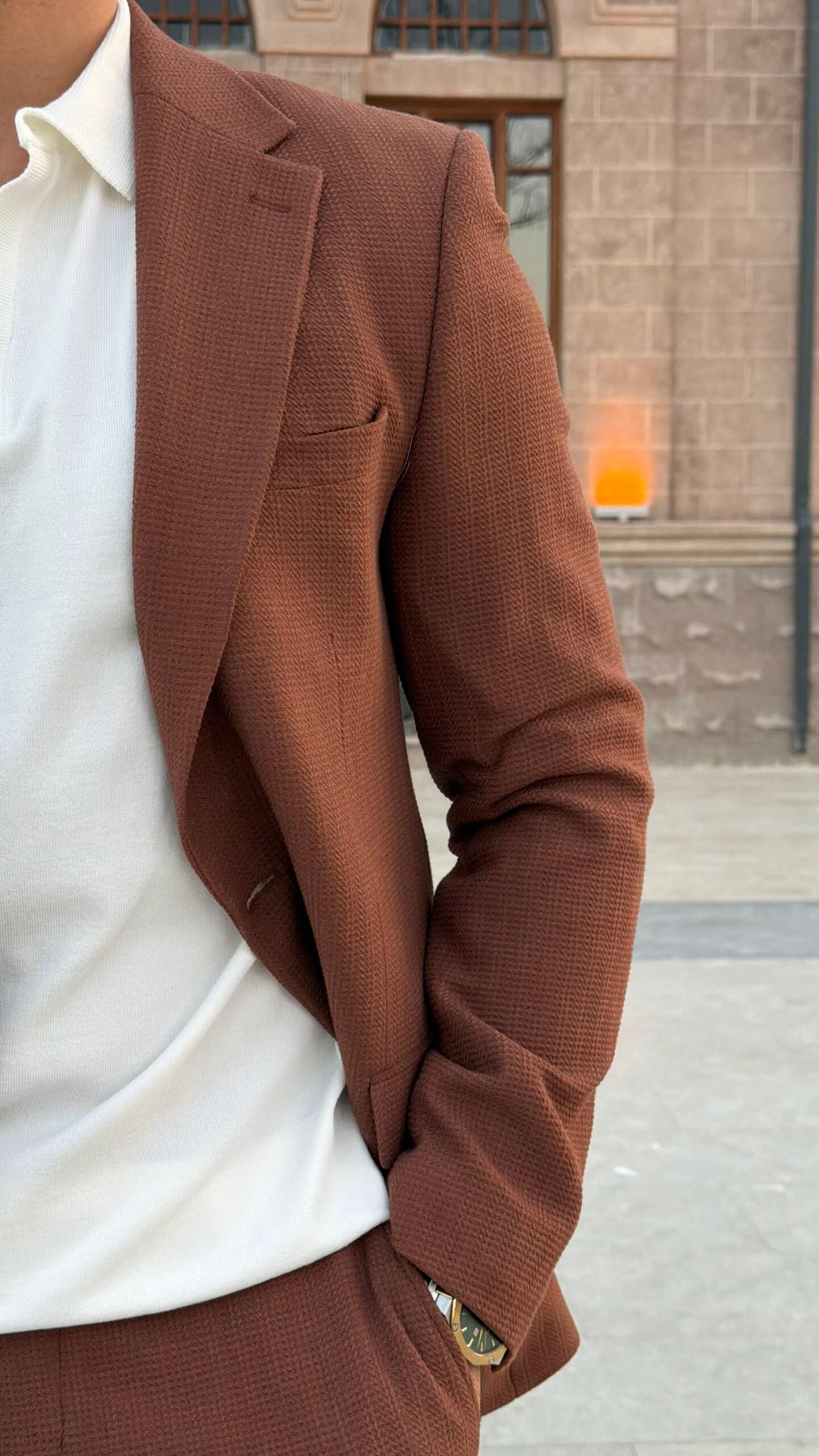 Men’s tile brown two piece suit with notch lapel jacket styled with white polo shirt and black loafers