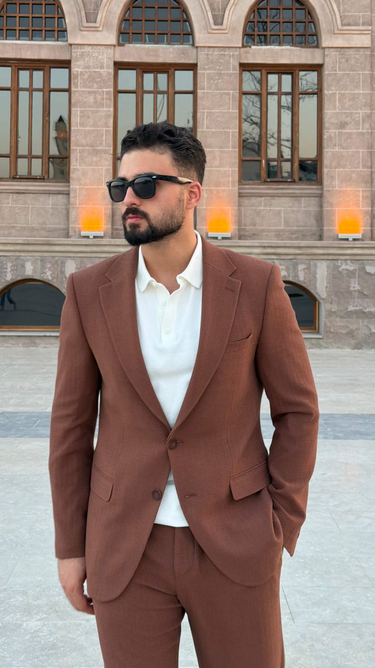 Men’s tile brown two piece suit with notch lapel jacket styled with white polo shirt and black loafers
