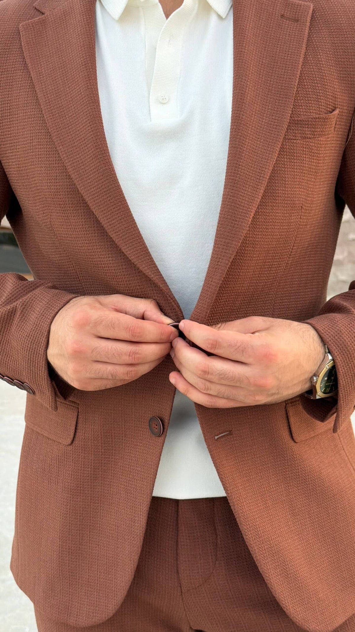 Men’s tile brown two piece suit with notch lapel jacket styled with white polo shirt and black loafers