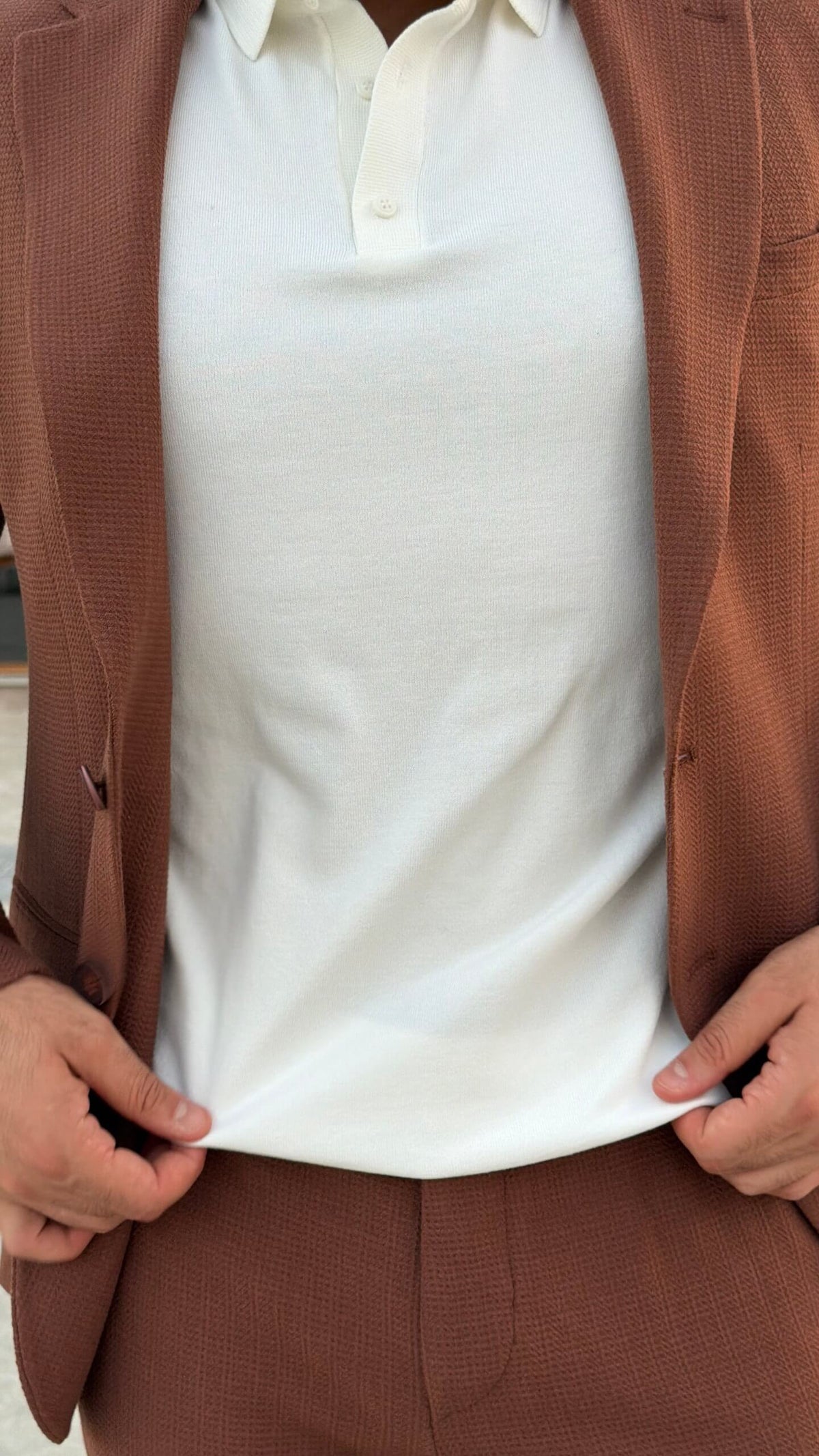 Men’s tile brown two piece suit with notch lapel jacket styled with white polo shirt and black loafers