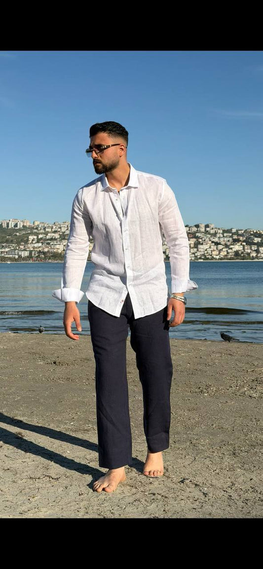 white linen collared dress shirt, standing by the water, sleeves rolled up, styled for summer.