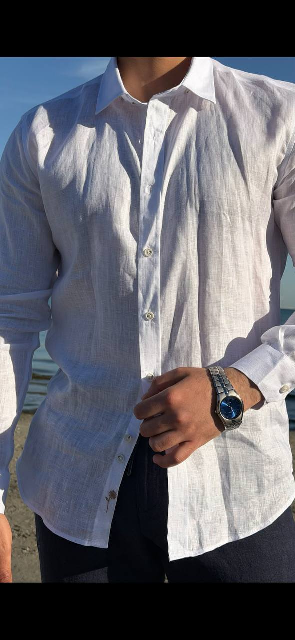 white linen collared dress shirt, standing by the water, sleeves rolled up, styled for summer.