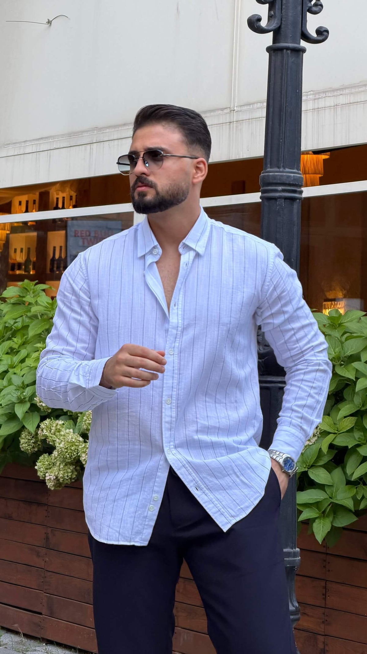 Men’s white long sleeve cotton button-up shirt styled with navy trousers and white sneakers