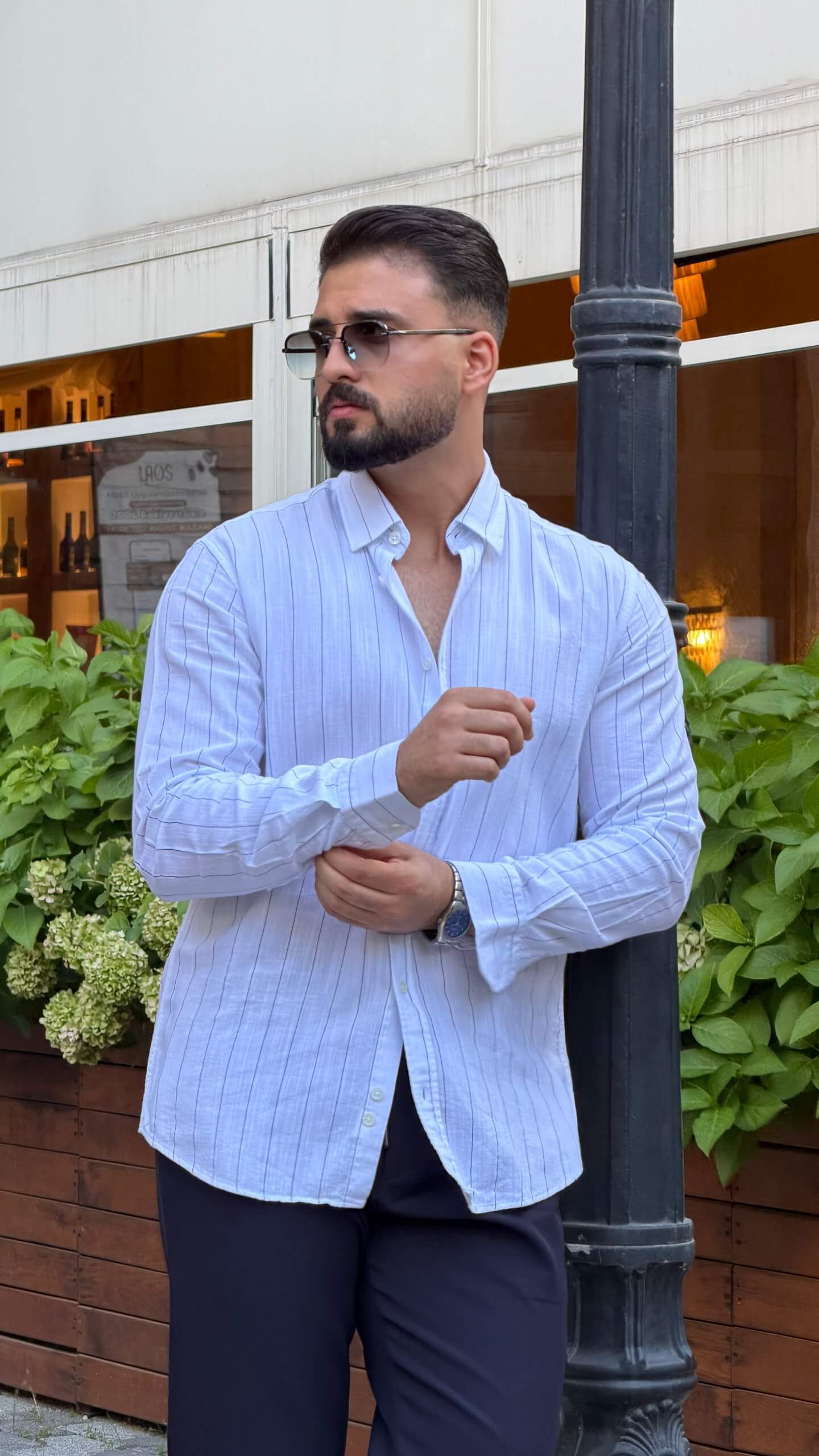 Men’s white long sleeve cotton button-up shirt styled with navy trousers and white sneakers
