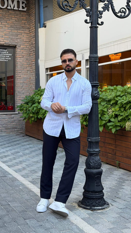 Men’s white long sleeve cotton button-up shirt styled with navy trousers and white sneakers