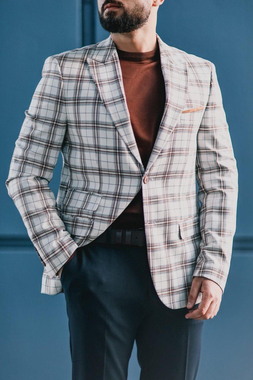 Men’s white plaid mono-collar slim-fit jacket styled with brown knit top and navy trousers