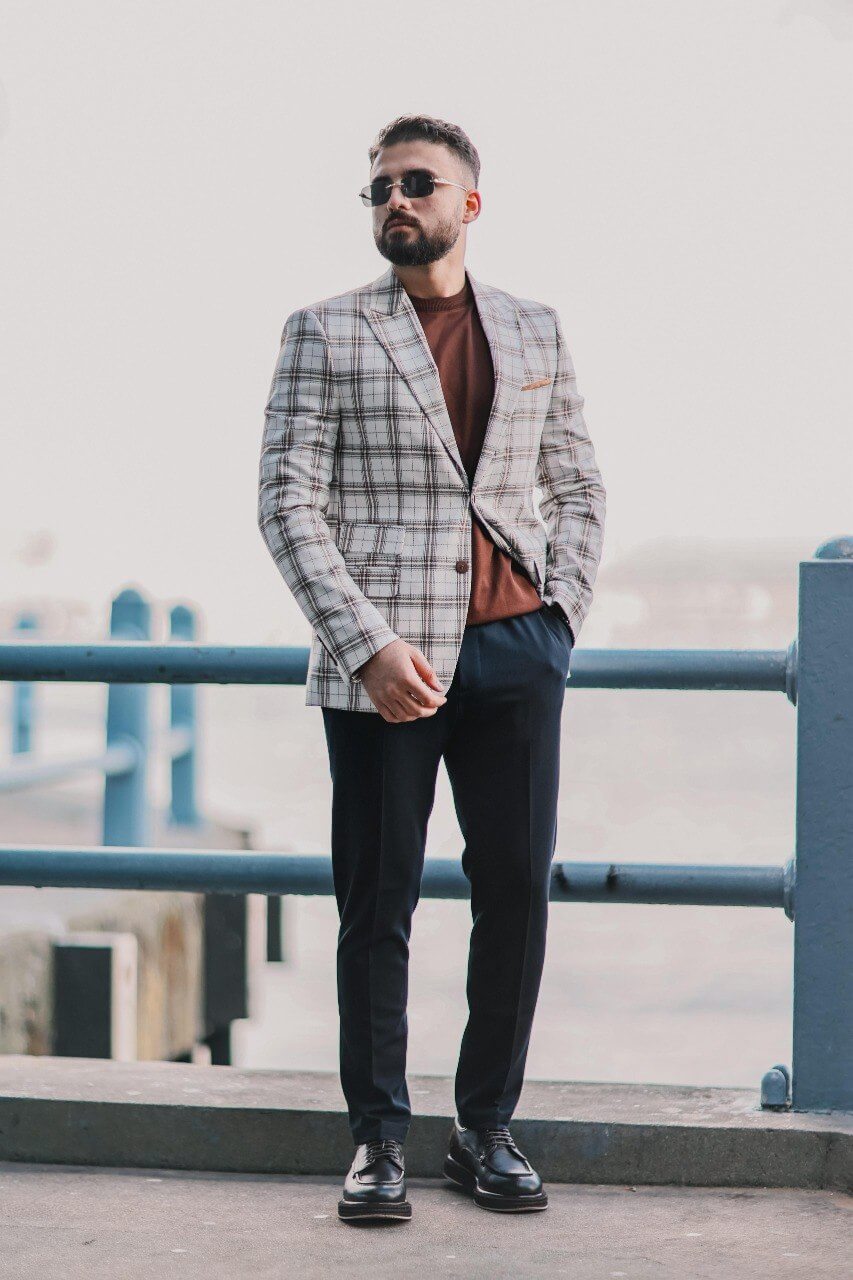 Men’s white plaid mono-collar slim-fit jacket styled with brown knit top and navy trousers