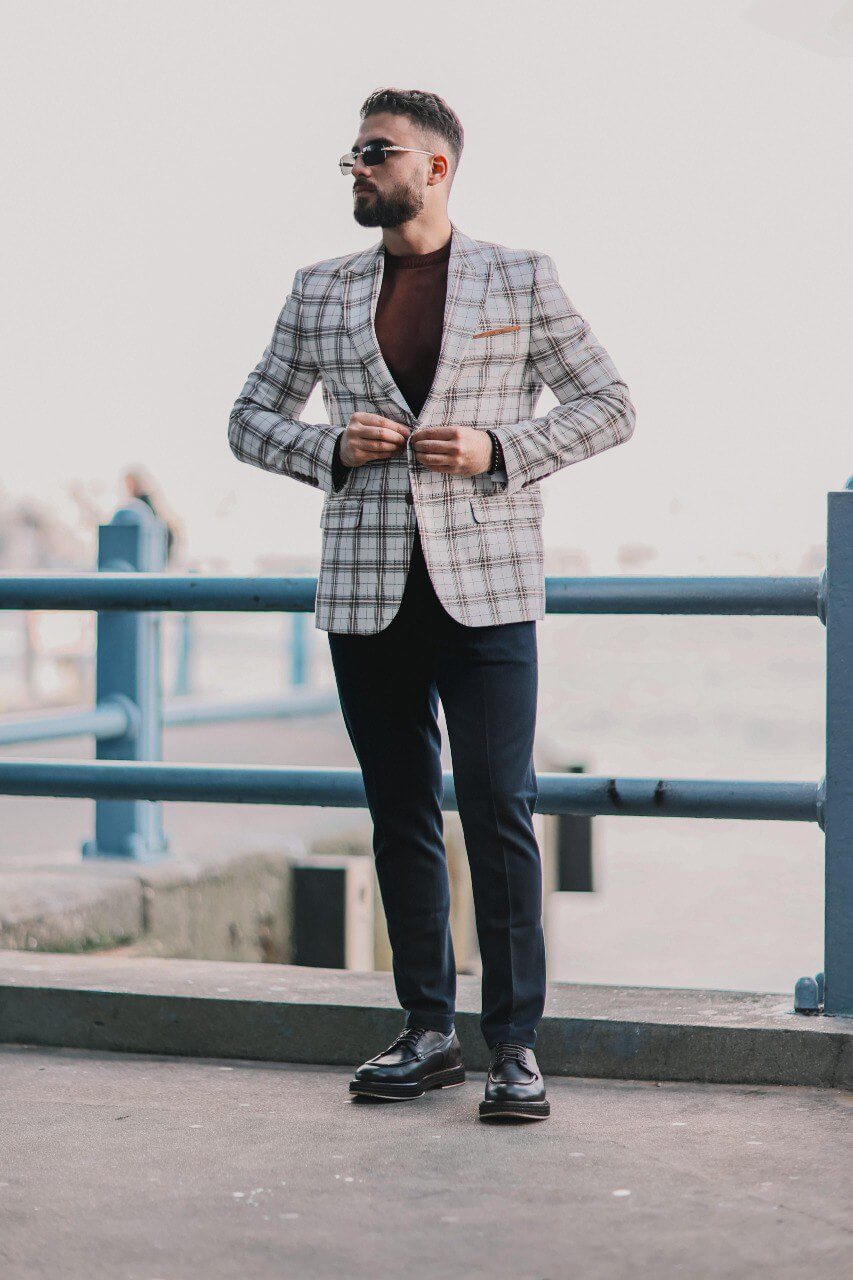 Men’s white plaid mono-collar slim-fit jacket styled with brown knit top and navy trousers