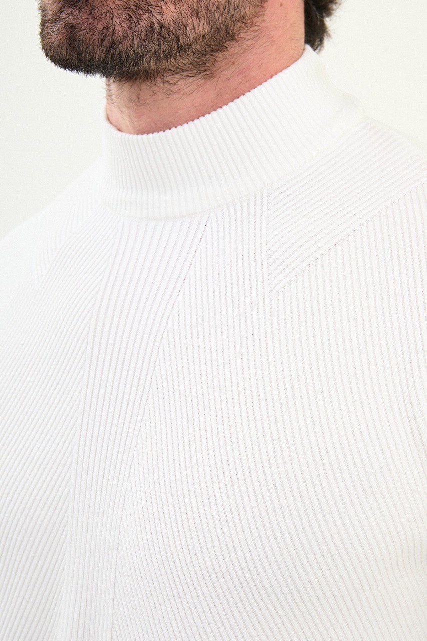 Men’s bright white slim-fit ribbed mock-neck cotton-blend sweater with multi-directional ribbing and diagonal chest panel, styled with dark denim.