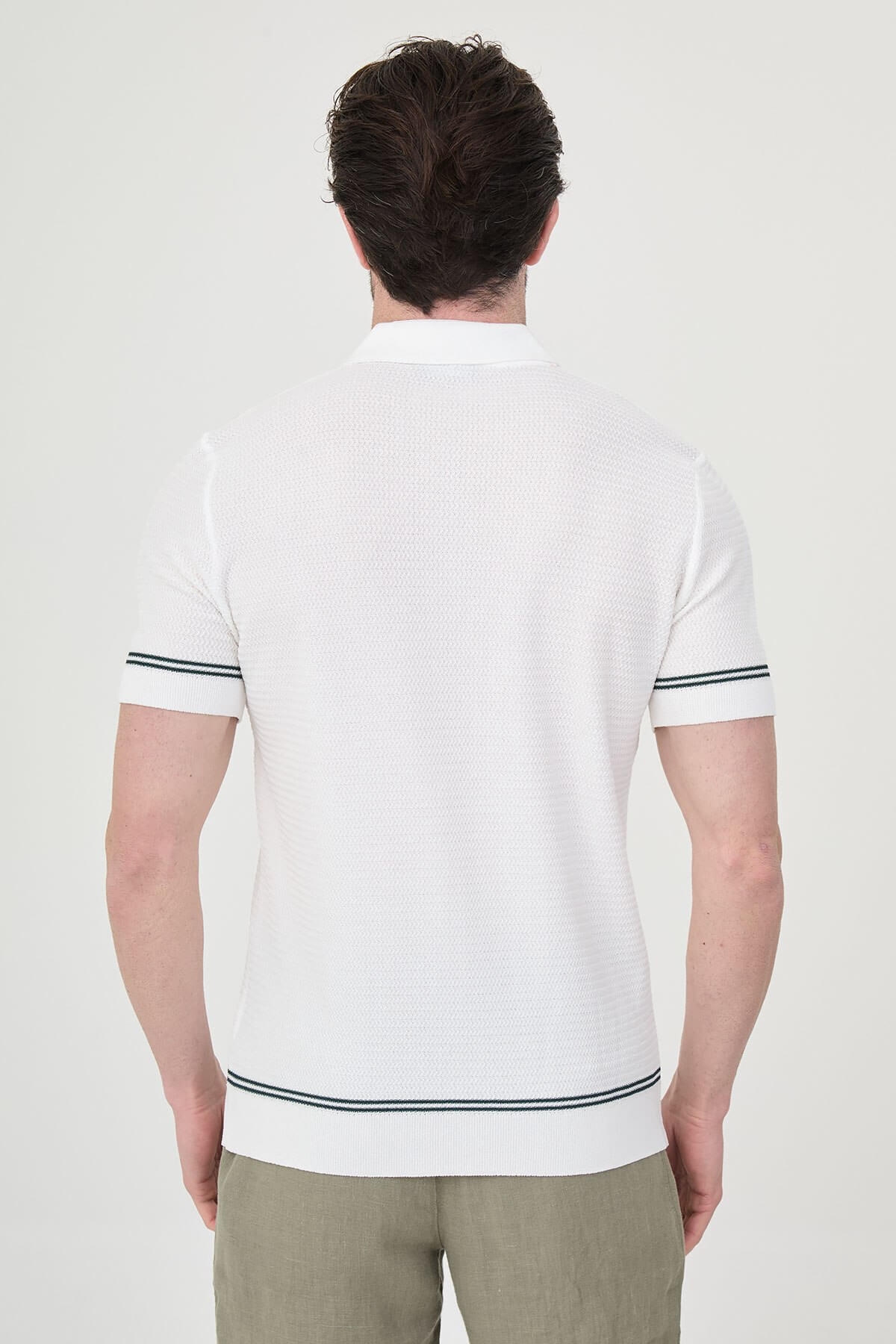 Man wearing white slim-fit quarter-zip polo t-shirt with dark stripe accents, styled with light brown trousers.