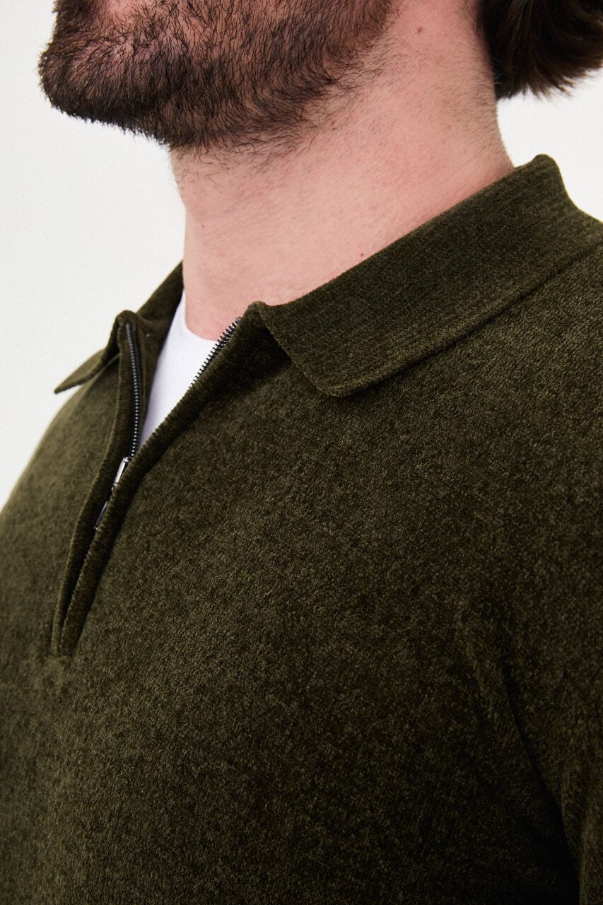 Men’s khaki polo neck knit sweater with zip collar detail styled with grey trousers for a refined fall winter smart-casual outfit.