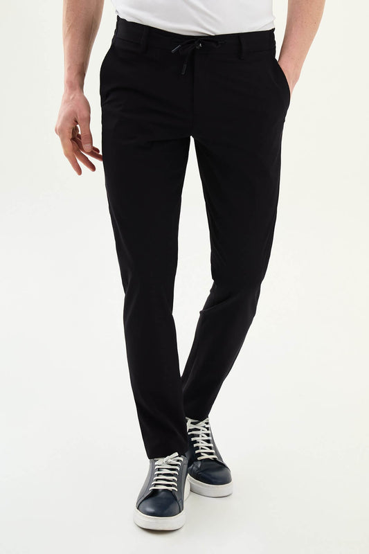 Man wearing navy blue slim-fit summer trousers styled with a white polo shirt and casual sneakers.