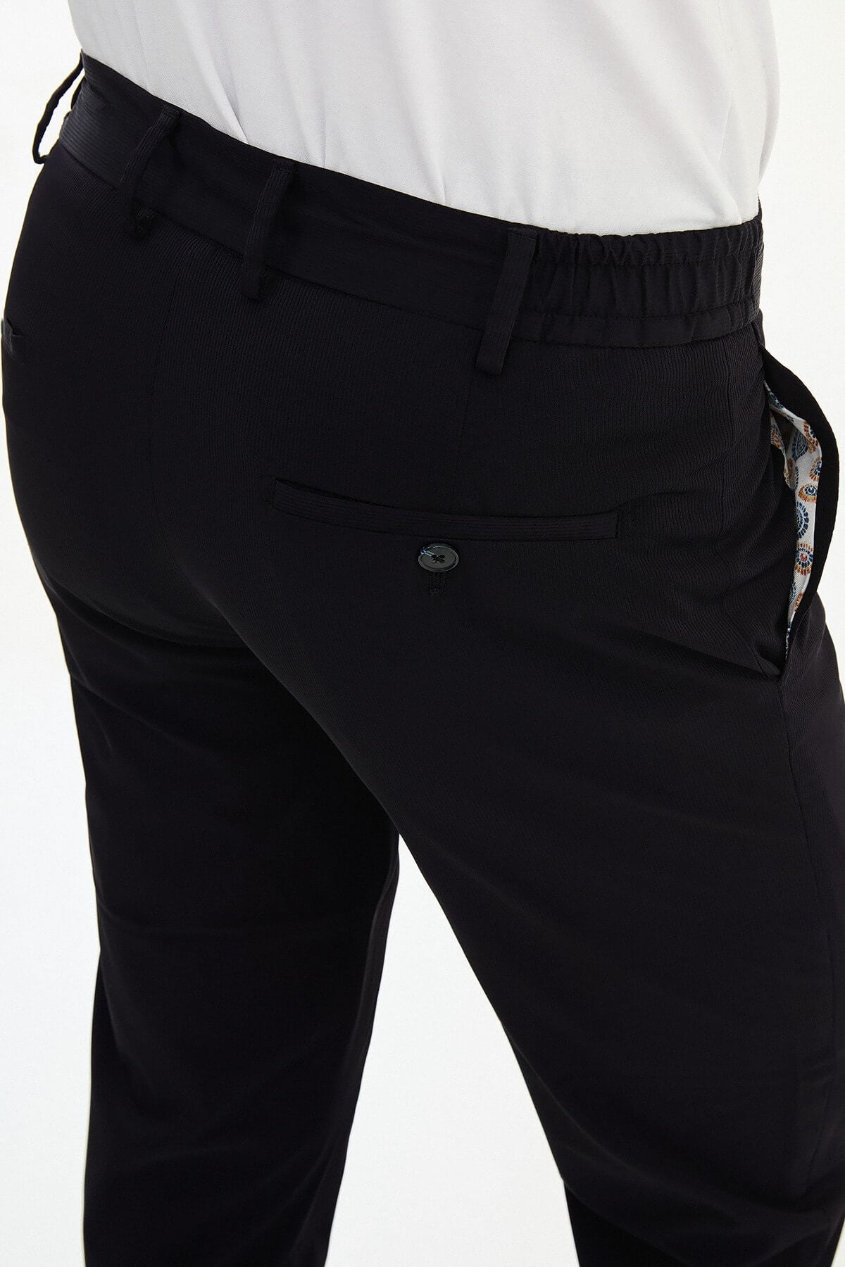 Man wearing navy blue slim-fit summer trousers styled with a white polo shirt and casual sneakers.