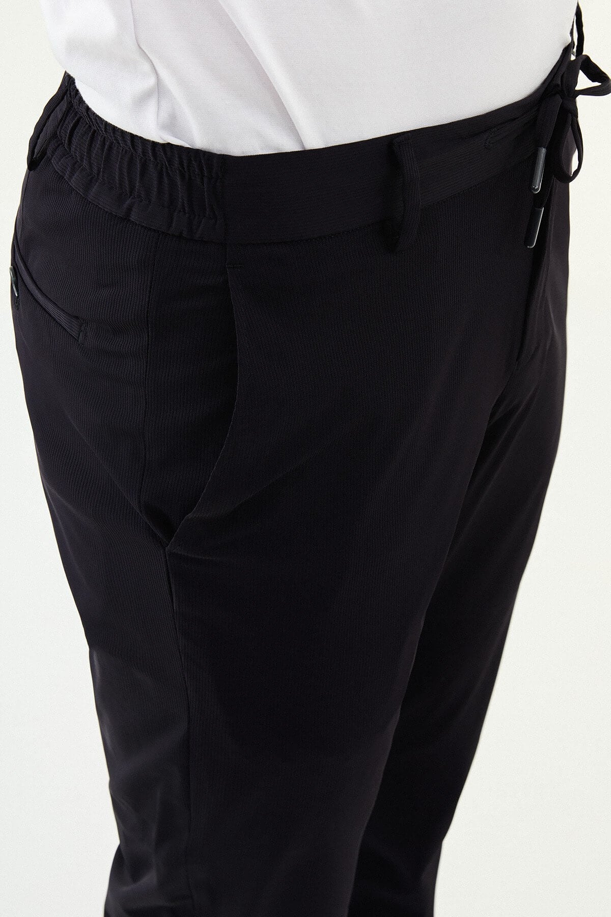 Man wearing navy blue slim-fit summer trousers styled with a white polo shirt and casual sneakers.