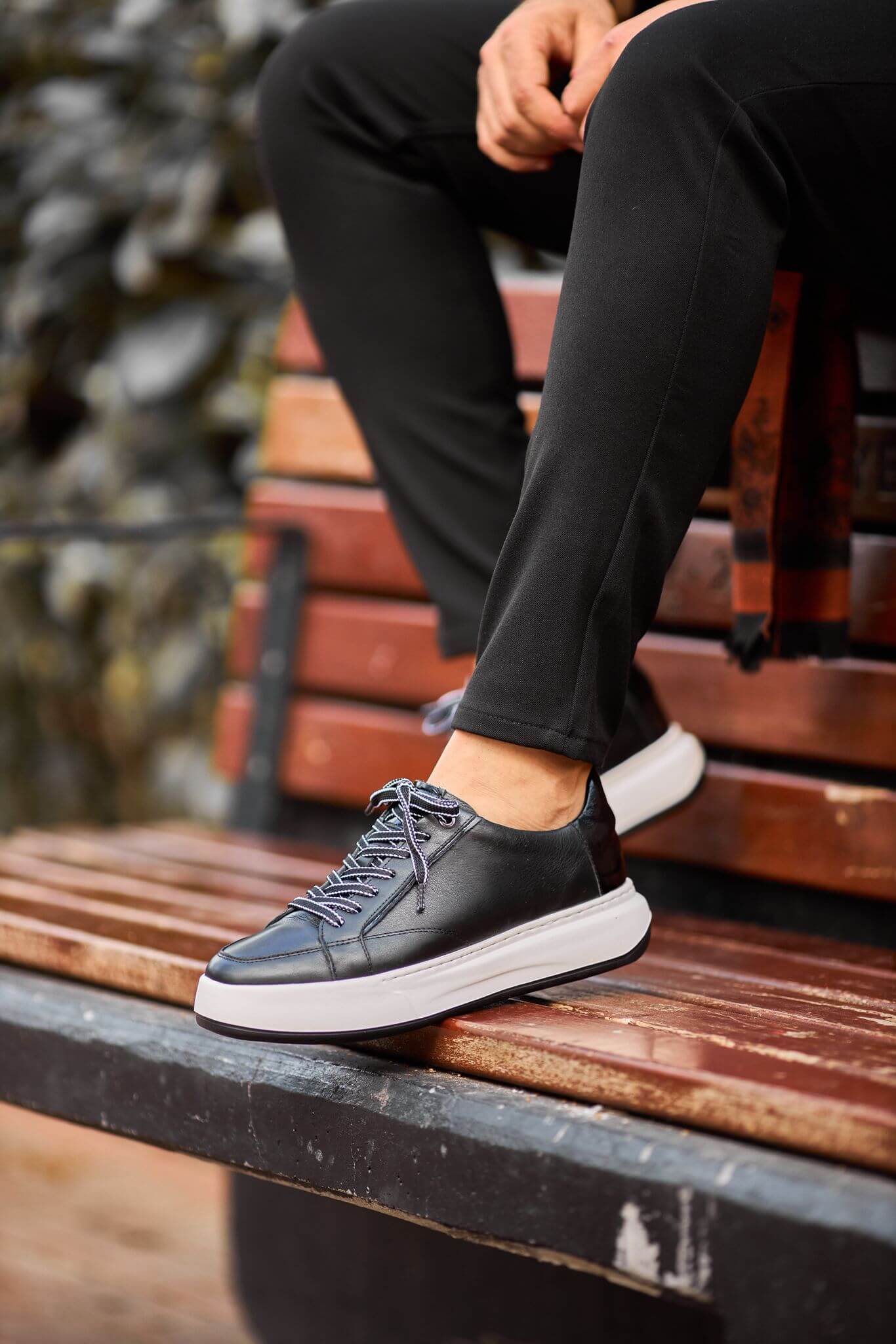 Black leather platform sneakers with white chunky sole on brick steps