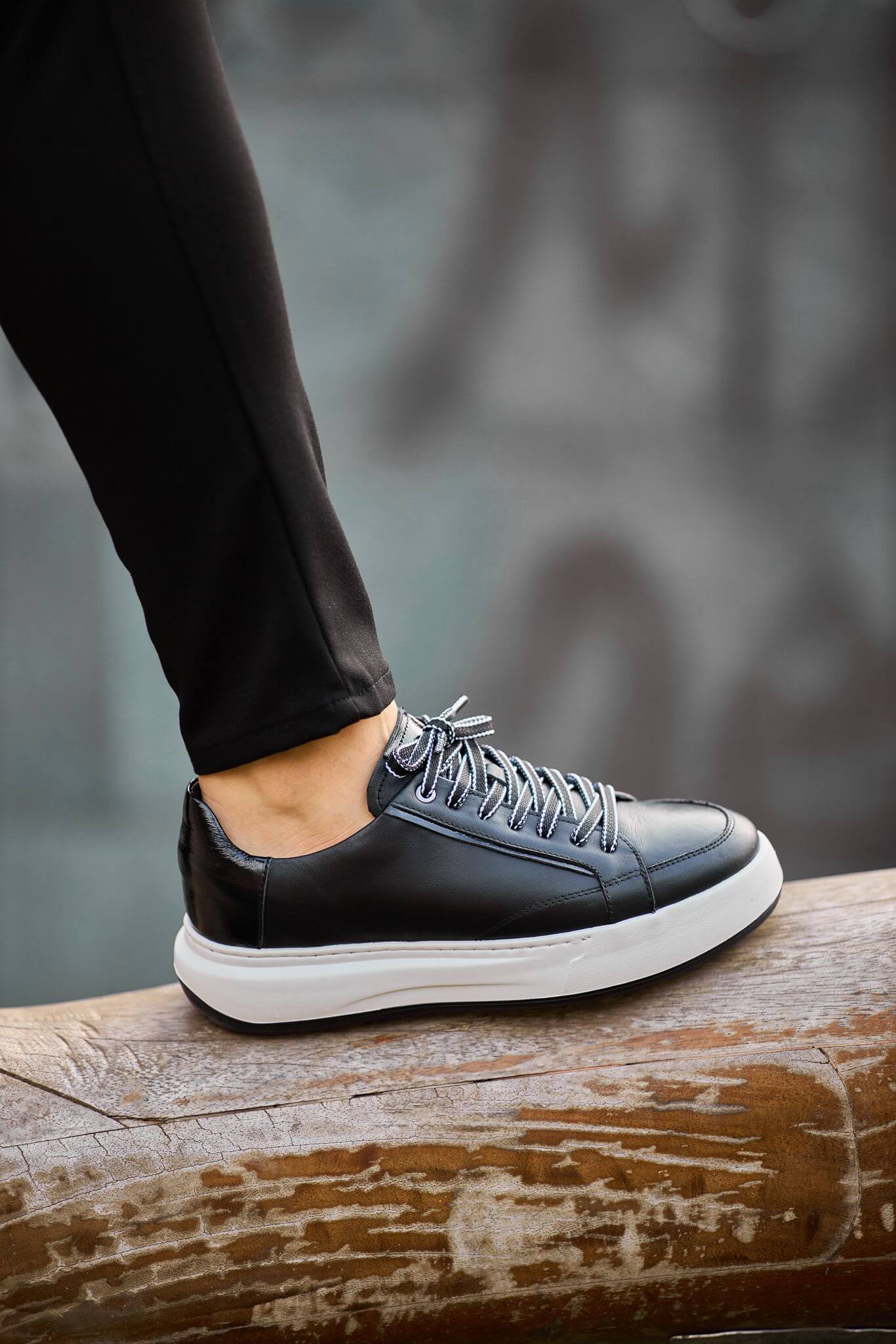 Black leather platform sneakers with white chunky sole on brick steps