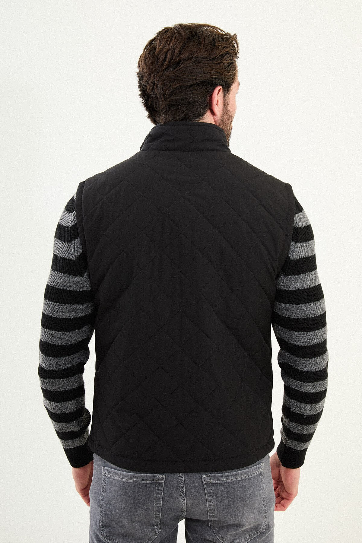 Men’s matte black technical vest with a stand collar and snap-flap utility pockets, designed for winter layering.