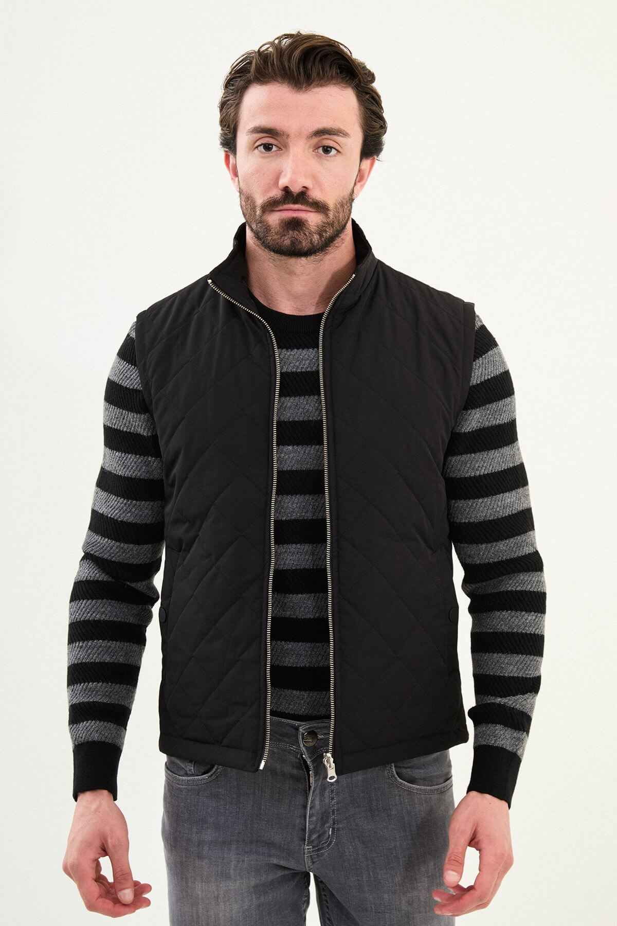 Men’s matte black technical vest with a stand collar and snap-flap utility pockets, designed for winter layering.